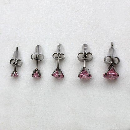 Pink round CZ studs with steel clutches in five sizes on a white surface