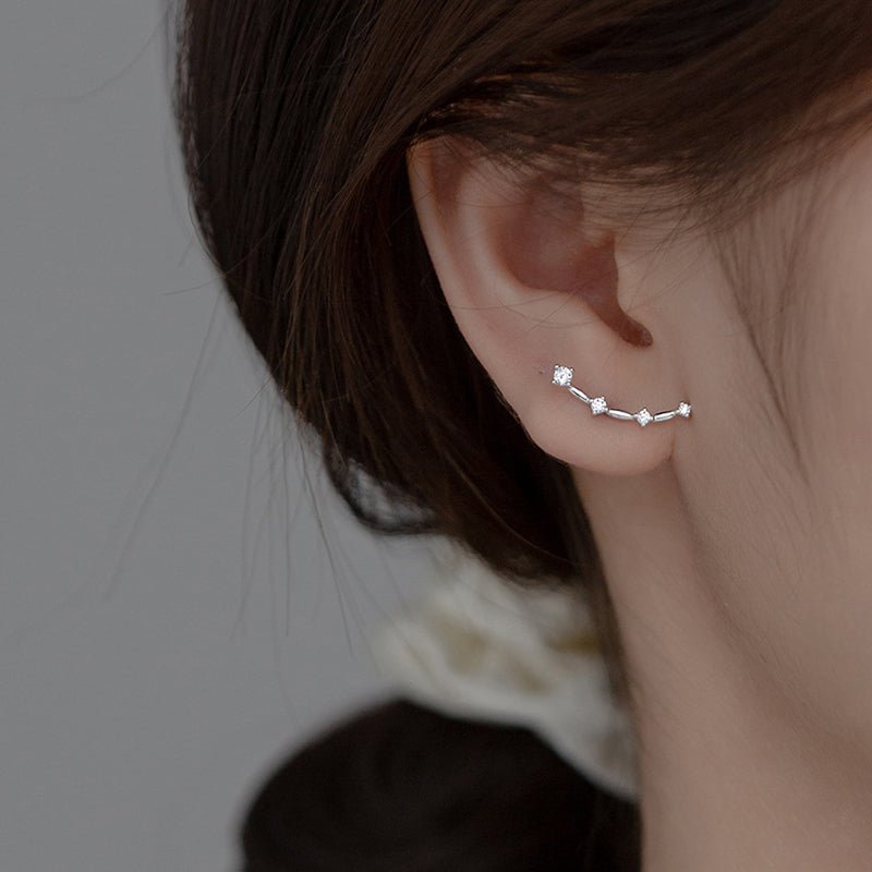 Sterling silver CZ ear climber worn on an earlobe, a slim curve of small stones following the lobe