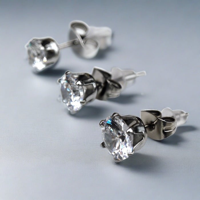 Sterling silver clear round CZ studs in three sizes with butterfly clutches on a gray background