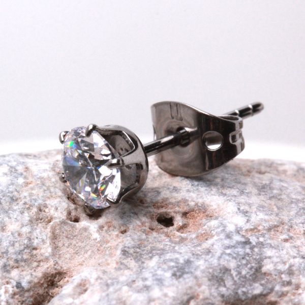 Titanium CZ stud with its metal clutch resting on gray stone