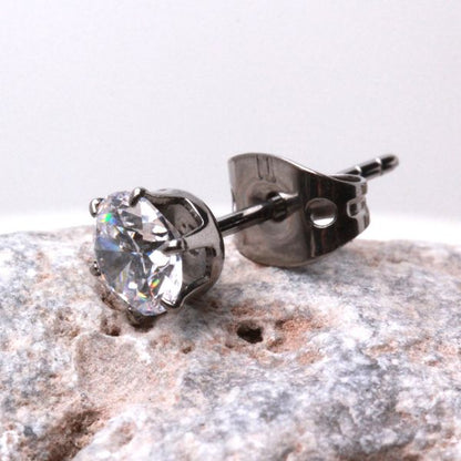 Titanium CZ stud with its metal clutch resting on gray stone