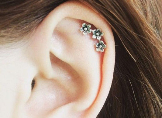 Triple flower earring worn on the upper ear, three small blossoms in a diagonal line