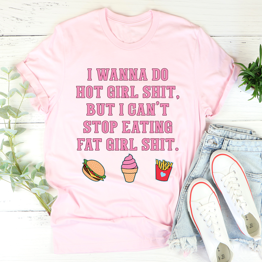 Pink cotton tee laid flat with denim and white sneakers, blunt block-letter slogan and burger, ice cream and fries icons.