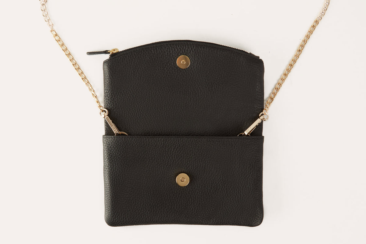 Black clutch opened out flat, showing the magnetic snaps and the gold-tone chain attached