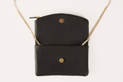 Black clutch opened out flat, showing the magnetic snaps and the gold-tone chain attached
