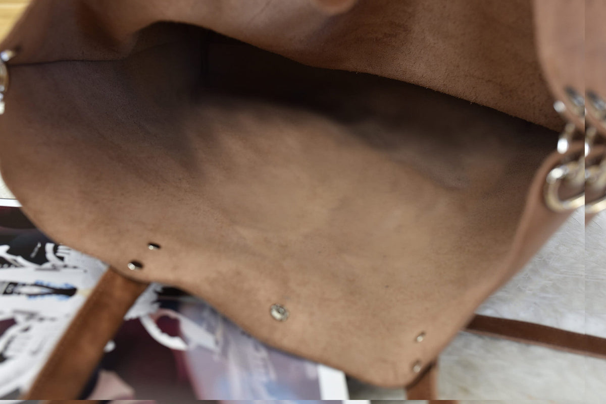 Inside the unlined caramel tote, showing the brushed underside of the leather and the strap rings