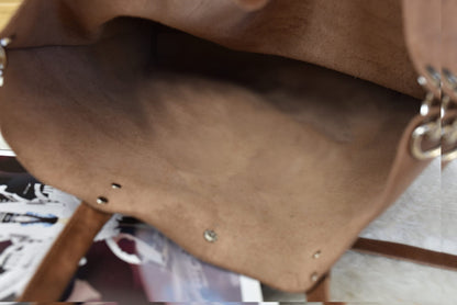 Inside the unlined caramel tote, showing the brushed underside of the leather and the strap rings