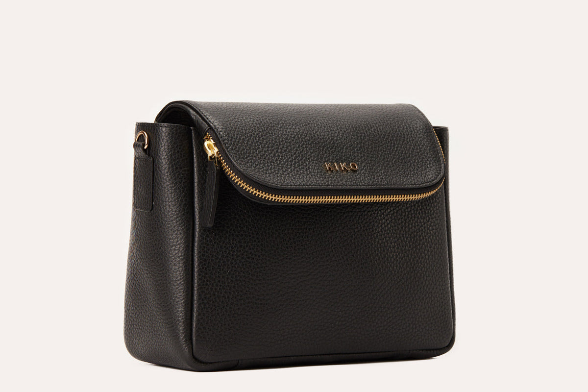 Black pebbled leather flap crossbody bag with a gold-tone zip along the flap edge, three-quarter view
