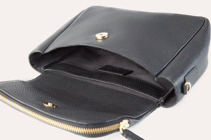 Flap lifted on the black crossbody bag, showing the magnetic snap, the inside sleeve and the zip running along the flap
