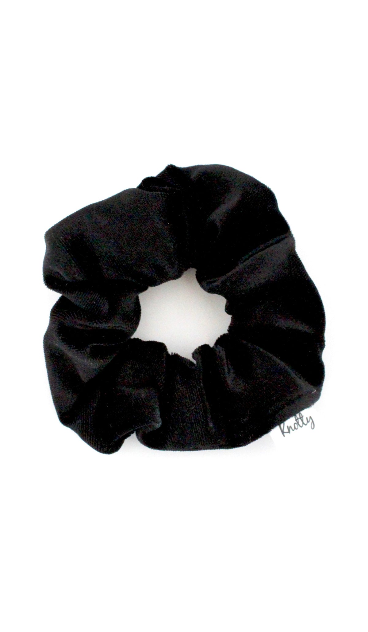 Black crushed velvet scrunchie lying flat on white, showing the soft gathered pile