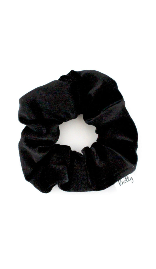 Black crushed velvet scrunchie lying flat on white, showing the soft gathered pile