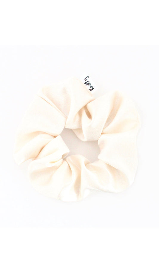 Cream washed satin scrunchie on white, gathered fabric with a small sewn label