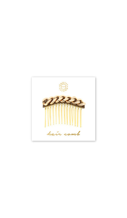 Decorative hair comb with a gold tone chain over metallic leather, on a branded card