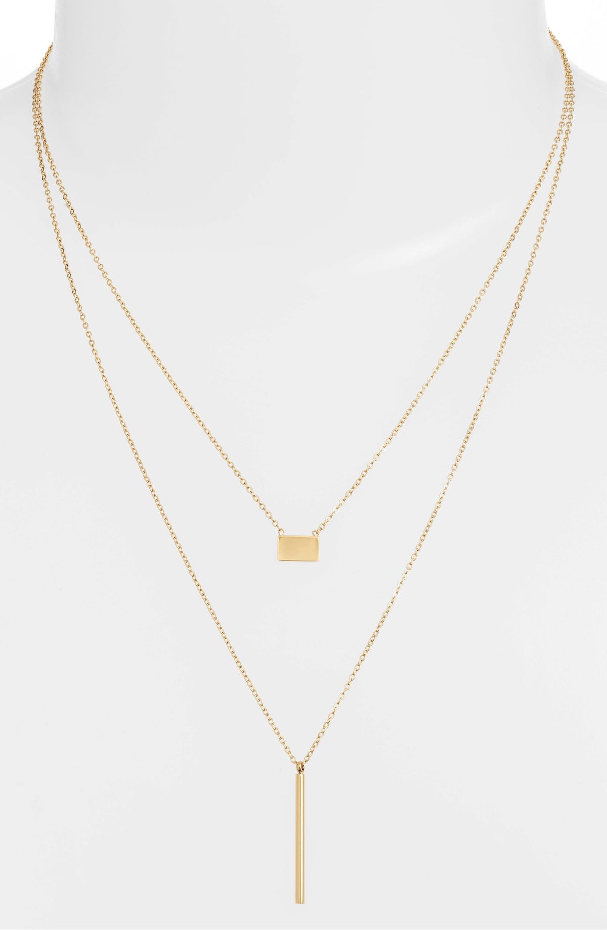 Double strand necklace on a white bust form, the short chain at the collarbone and the bar drop below