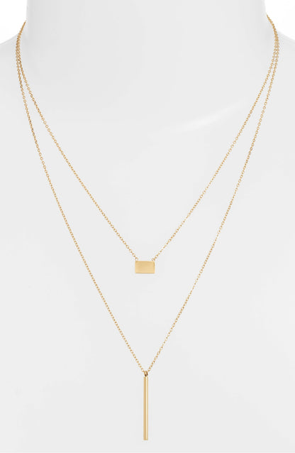 Double strand necklace on a white bust form, the short chain at the collarbone and the bar drop below