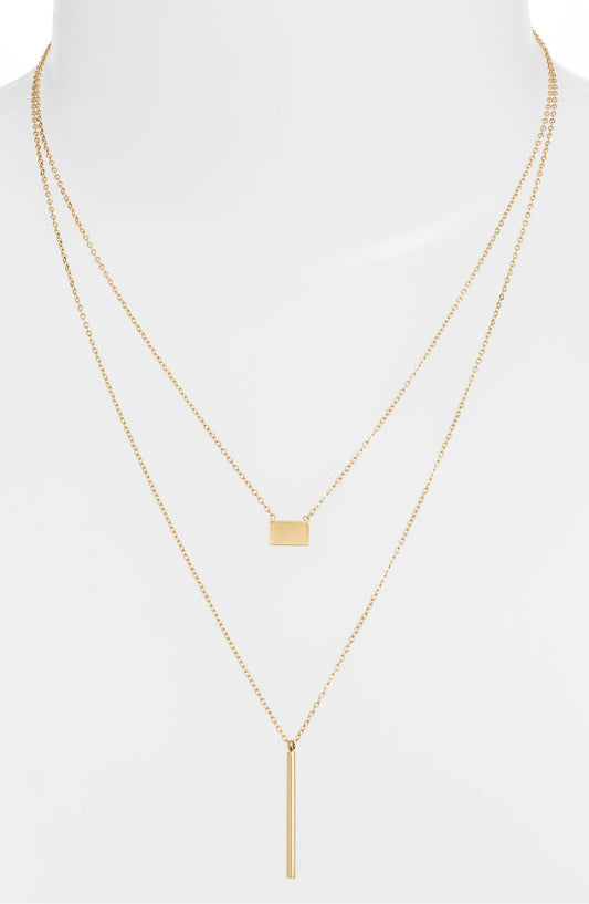 Double strand necklace on a white bust form, the short chain at the collarbone and the bar drop below