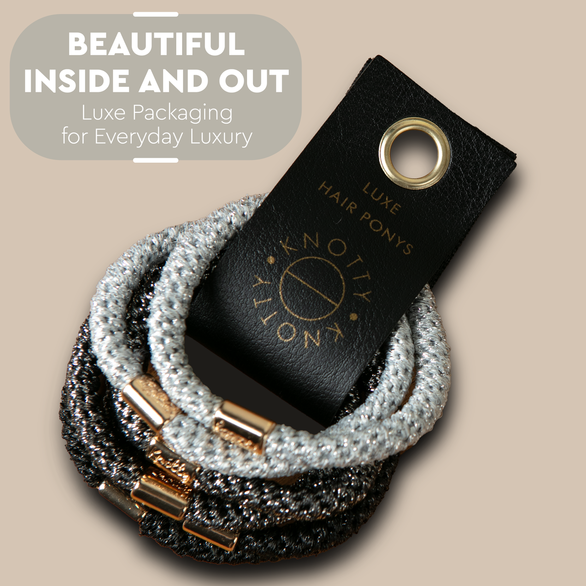 Metallic hair ties in silver, black and gold tones looped on a black branded tab