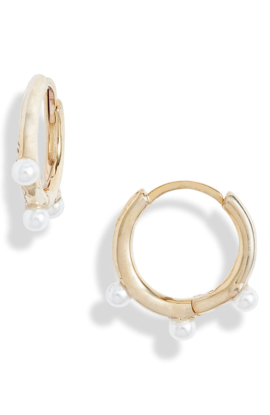 Pearl huggie hoop earrings in a pale gold color with small imitation pearls dotted along the lower edge