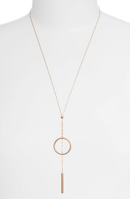 Lariat necklace on a white bust form, the circle and bar hanging low on the chest