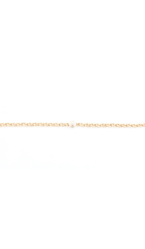 Close up of a thin braided headband in gold tone with its polished bead closure