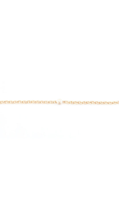 Close up of a thin braided headband in gold tone with its polished bead closure