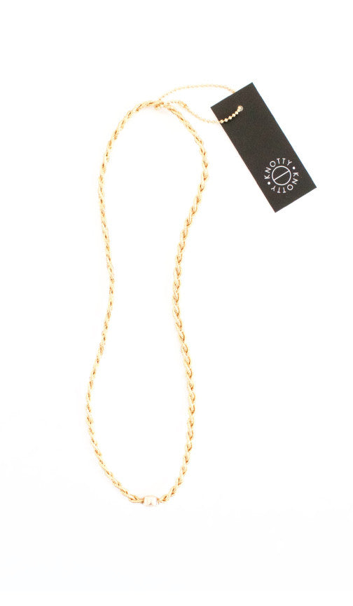 Gold tone braided metallic headband laid out on white with its hang tag