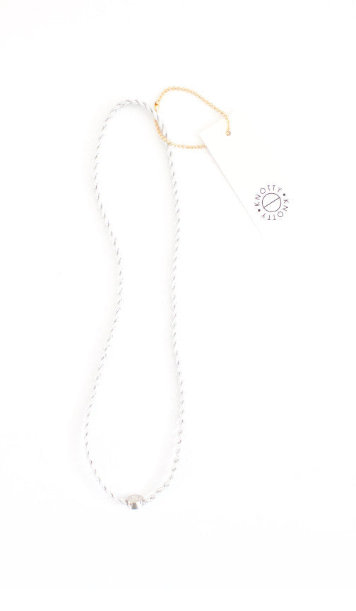 Silver braided metallic headband laid out full length on white with its hang tag