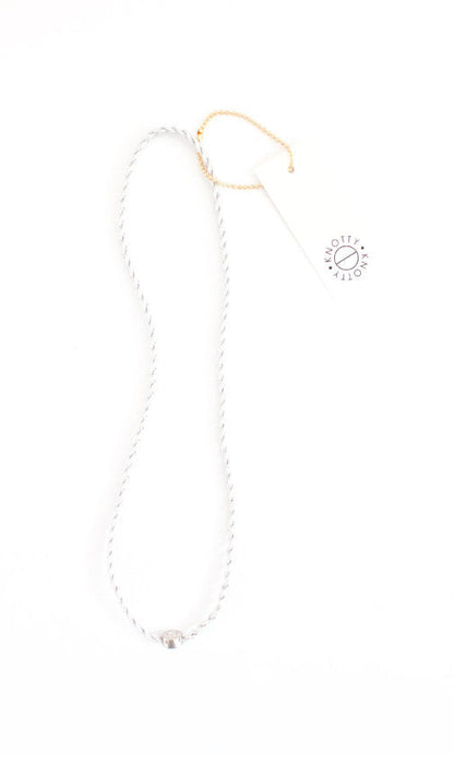 Silver braided metallic headband laid out full length on white with its hang tag