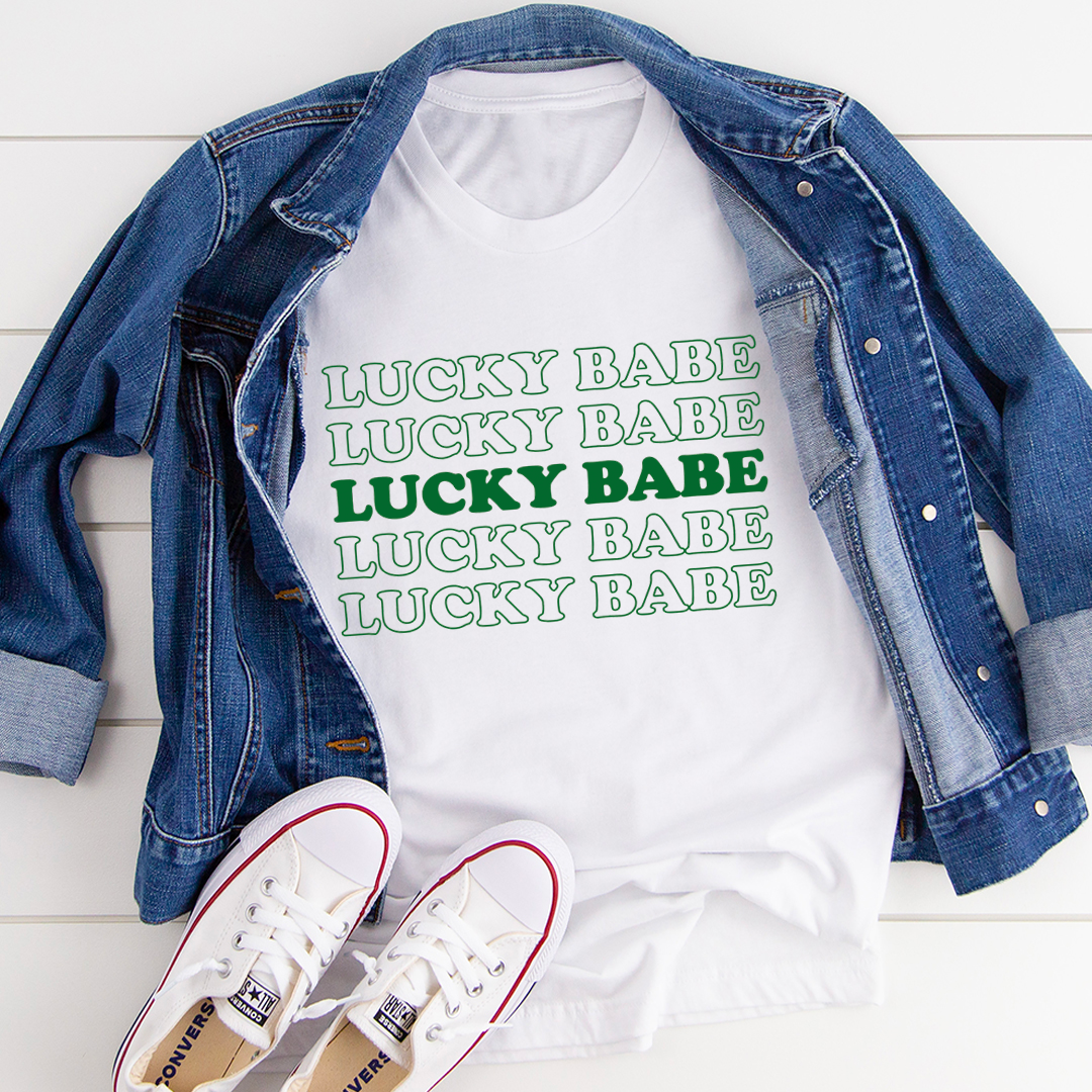 White cotton graphic T-shirt featuring a Lucky Babe design on the front.