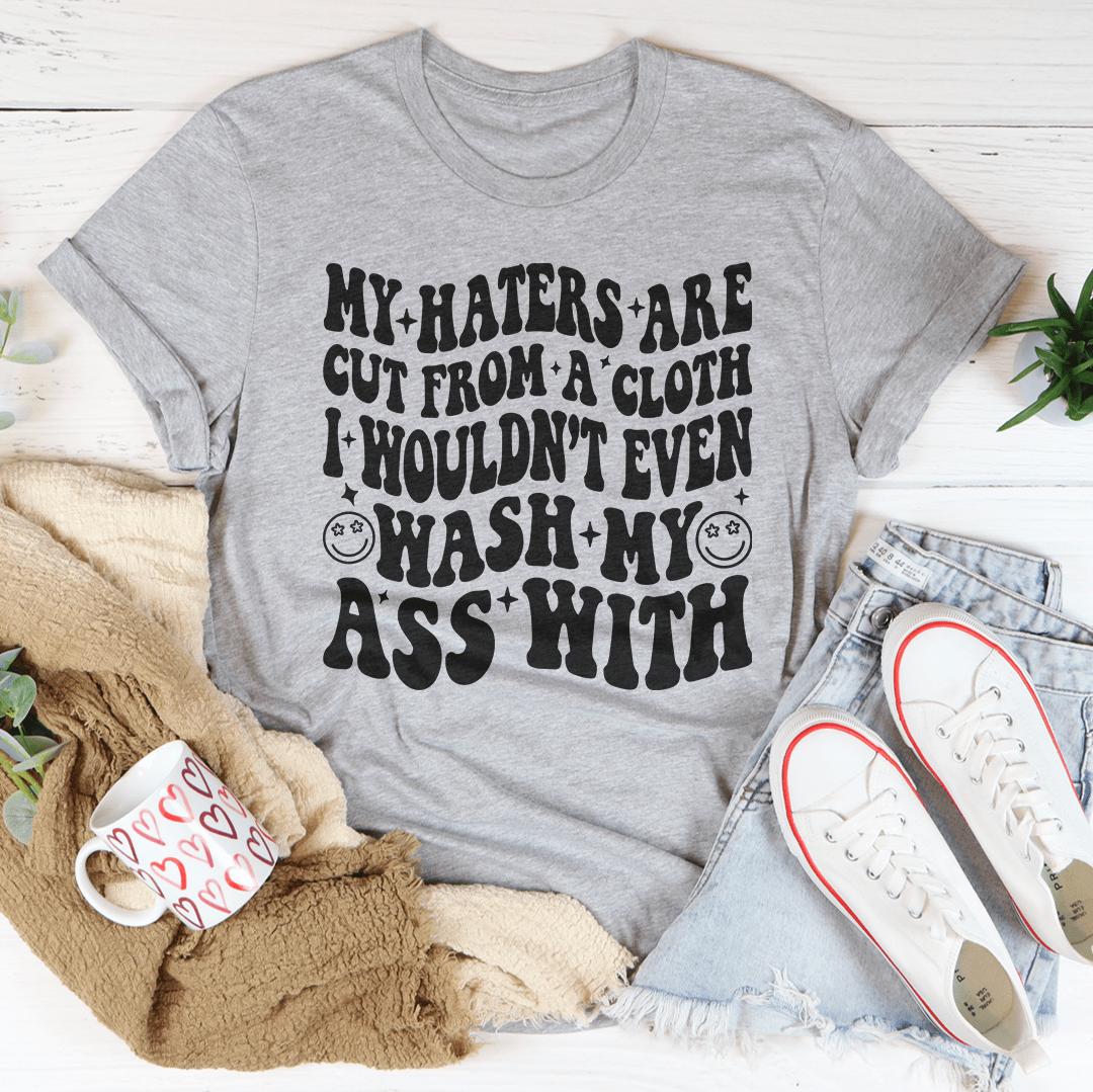 Statement cotton tee shirt with bold graphic "My haters are cut from a cloth" in heather peach color.