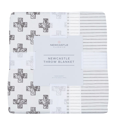 Folded bamboo muslin throw blanket in its band, printed with gray stamped crosses and thin dark pencil stripes