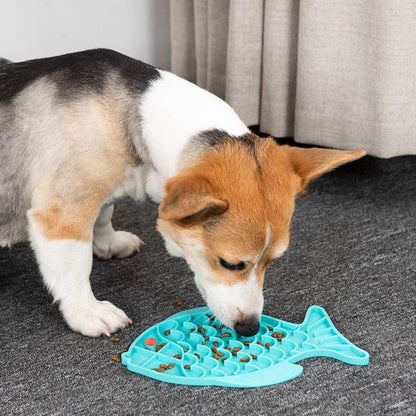 Corgi puppy licking a blue fish shaped silicone mat on the floor.