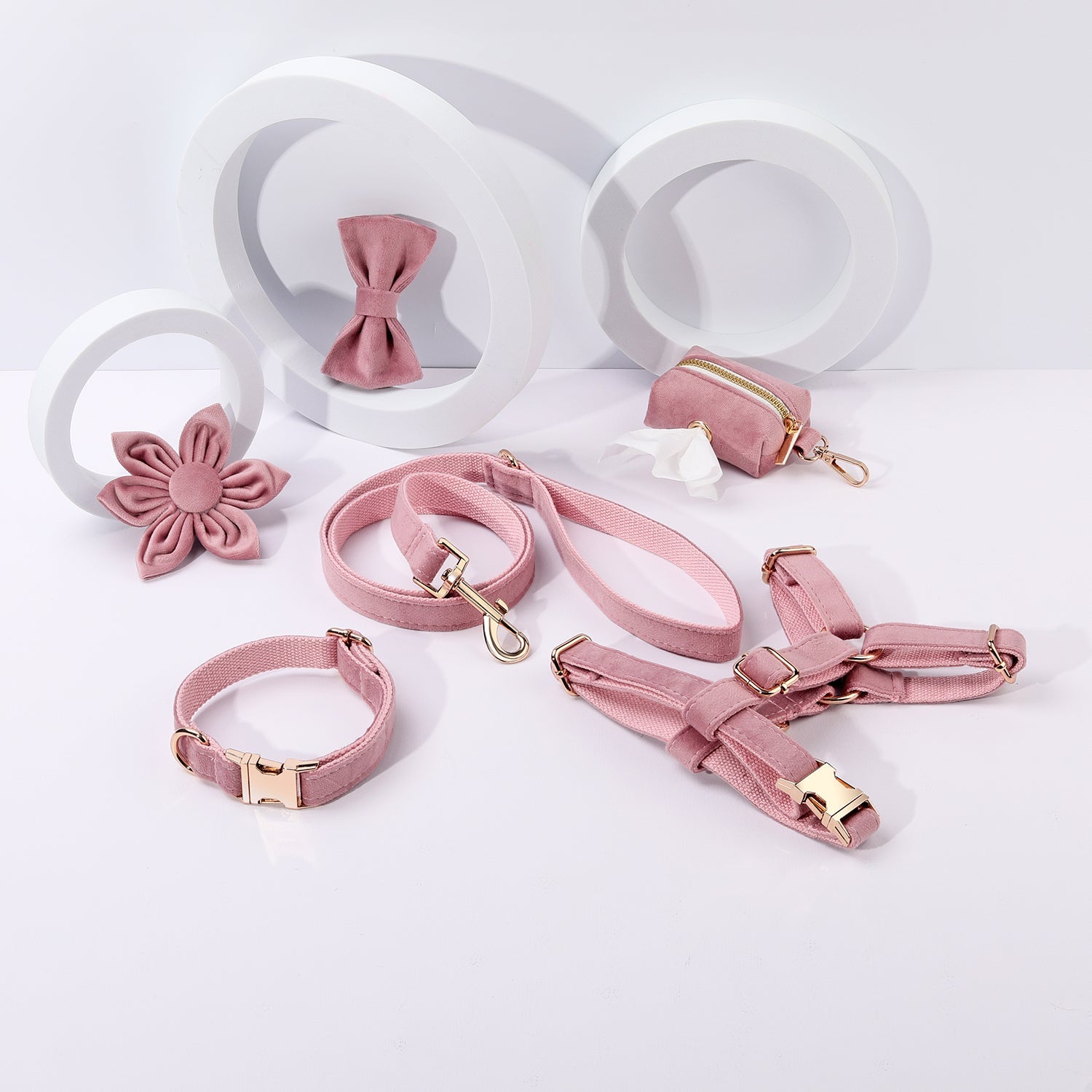 Flat lay of the pink walking set: harness, collar, leash, bowtie and waste bag holder.