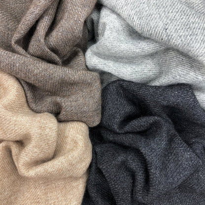 Four folded cashmere scarves close up in espresso brown, light gray, oatmeal and charcoal