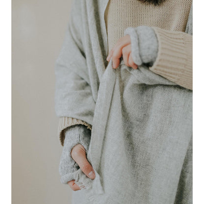 Close view of the gray cashmere scarf gathered in one hand, showing its soft brushed weave