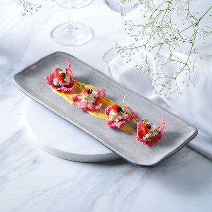 Gray rectangular platter on marble, plated and set on a round white charger.