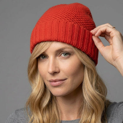 Fire red cashmere beanie on a model adjusting the ribbed cuff