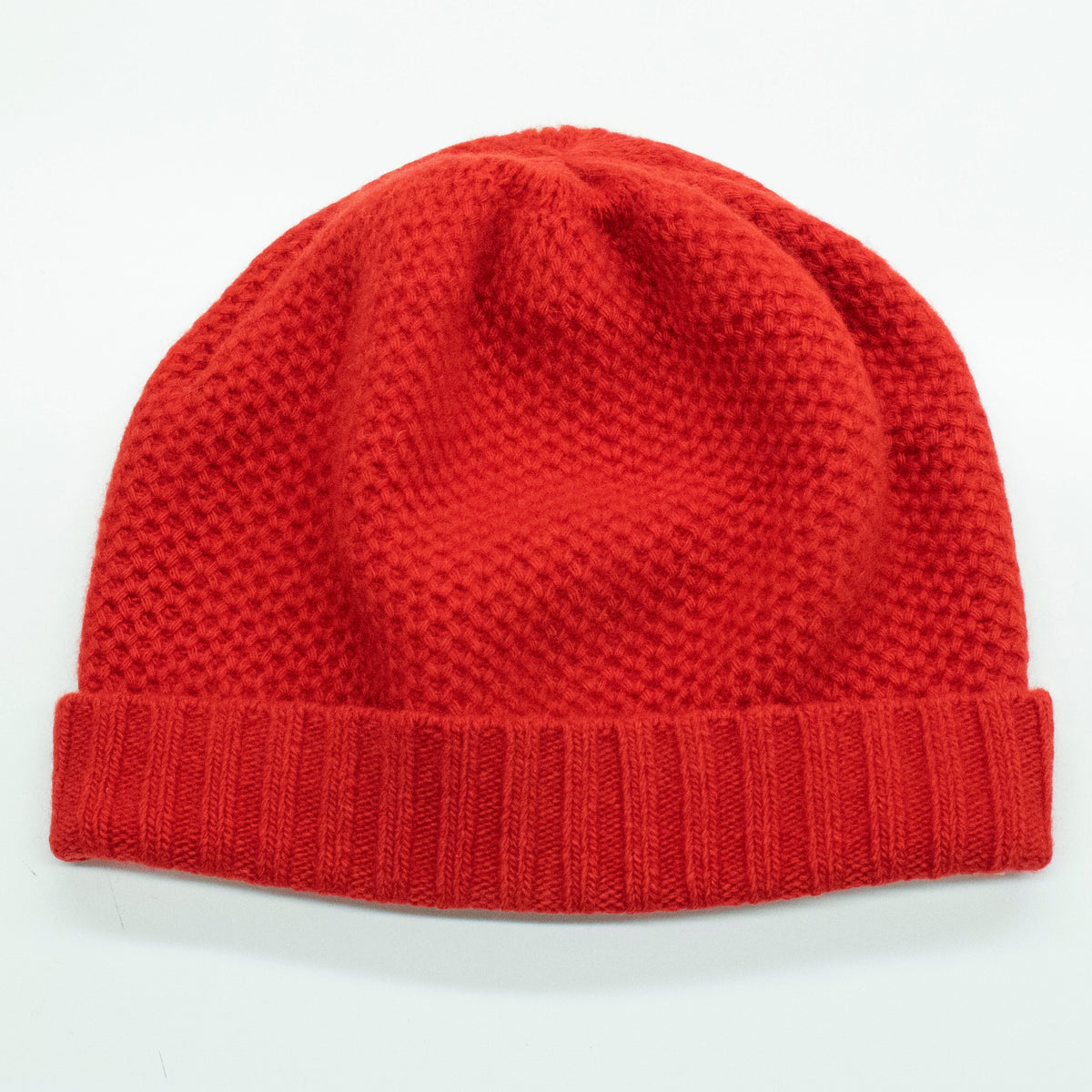 Fire red cashmere beanie laid flat, honeycomb texture above a ribbed cuff