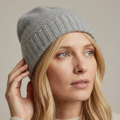 Light gray cashmere beanie on a model touching the brim, honeycomb stitch and ribbed cuff