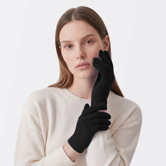 Model wearing black cashmere gloves with a cream knit sweater