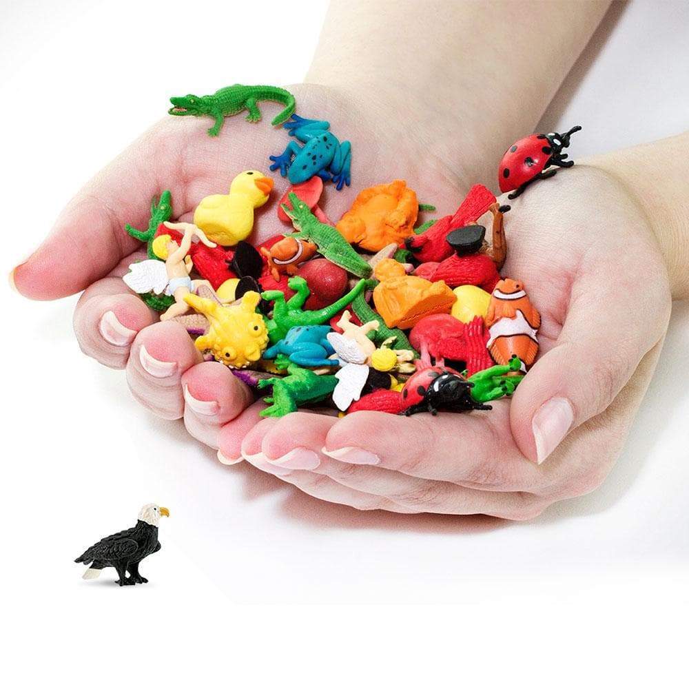 Cupped hands holding a mixed pile of Good Luck Minis, one bald eagle figurine placed below for scale