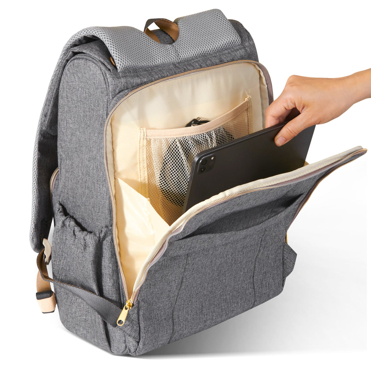 Hand sliding a tablet into the laptop sleeve of the canvas diaper backpack.