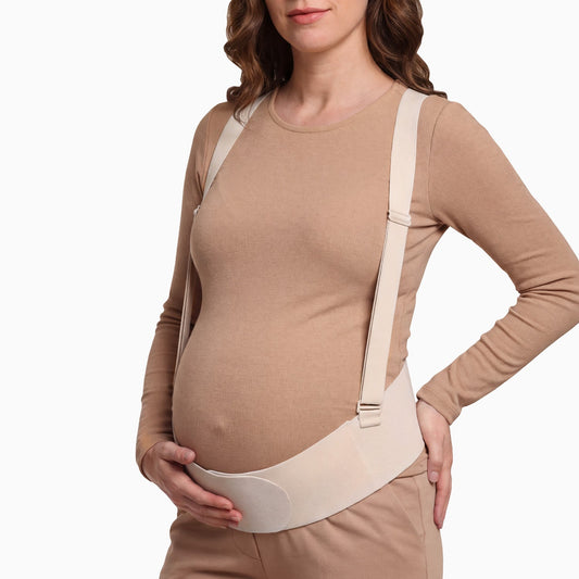 Pregnant woman wearing the support band under a fitted top, hand on hip.