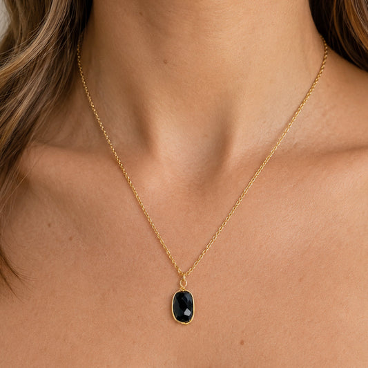 Black quartz pendant necklace worn at the collarbone on bare skin