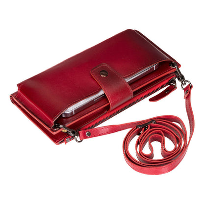 Crossbody phone wallet in Red, a burnished crimson leather, with the strap coiled beside it