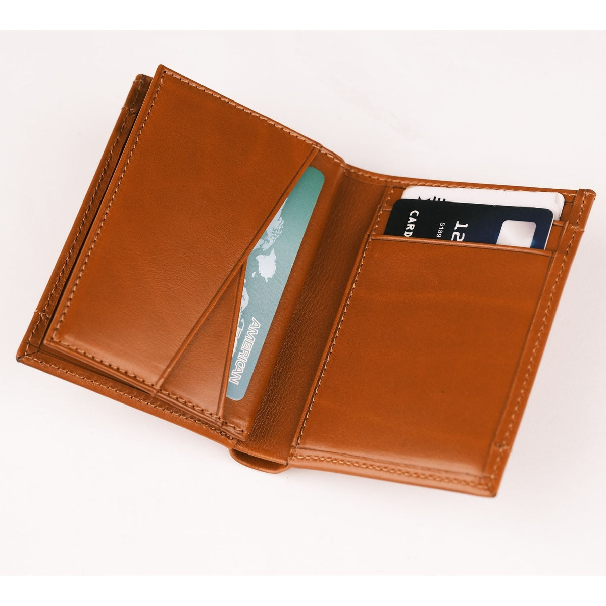 Tan leather AirTag wallet opened like a book, card slots on both sides with cards tucked in