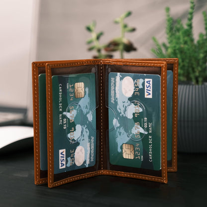 Tan leather card holder opened out flat, a card in each of its clear flip sleeves