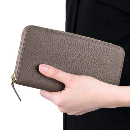 Women's zip around wallet in Mink, a pebbled gray-brown leather, held in one hand
