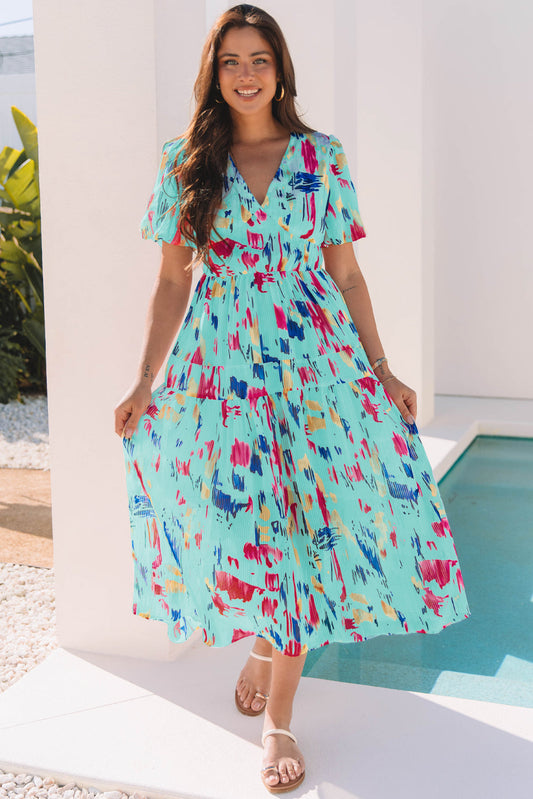 Aqua abstract print midi dress with puff sleeves, model holding the skirt by a pool