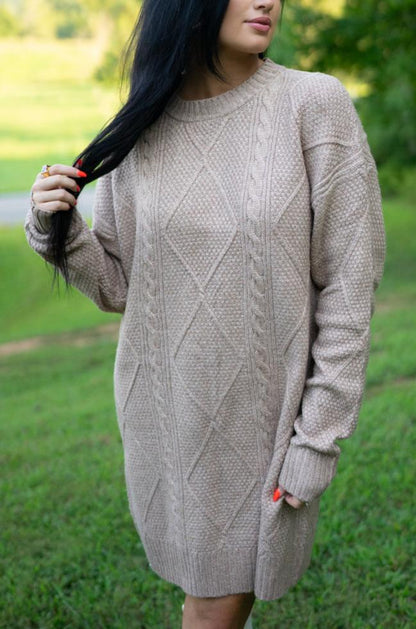 Taupe cable knit sweater dress, model with a hand in her hair, front view